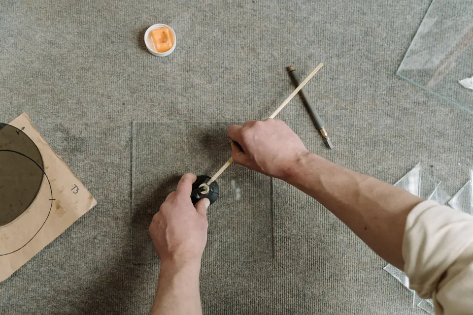 Manos cortando una pieza de vidrio en un banco de taller